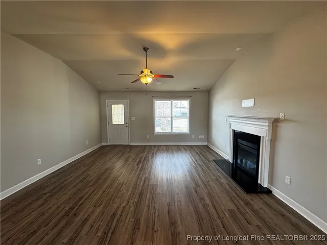 an empty room with wooden floor fireplace and window