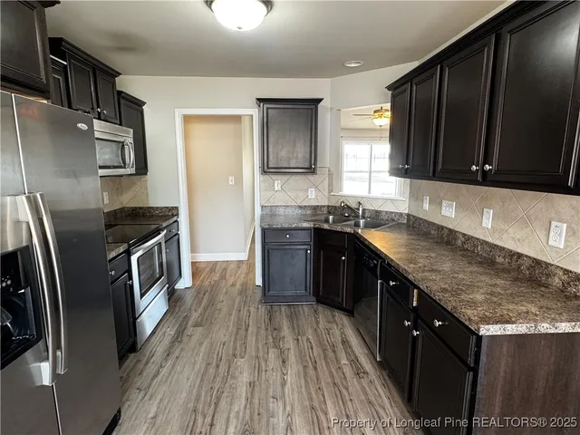 a kitchen with stainless steel appliances granite countertop a stove a sink dishwasher a refrigerator and wooden cabinets