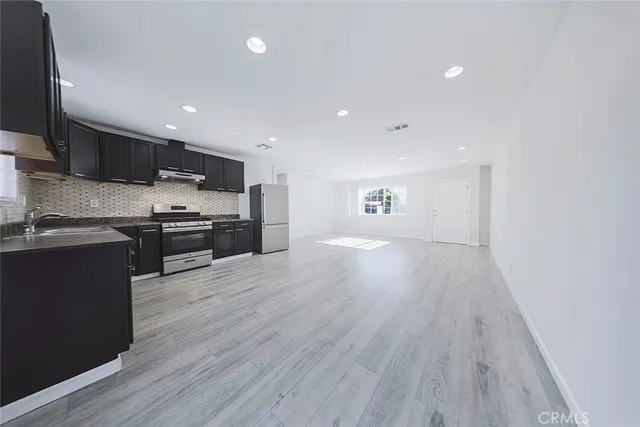 a kitchen with stainless steel appliances granite countertop a stove top oven a sink and a refrigerator