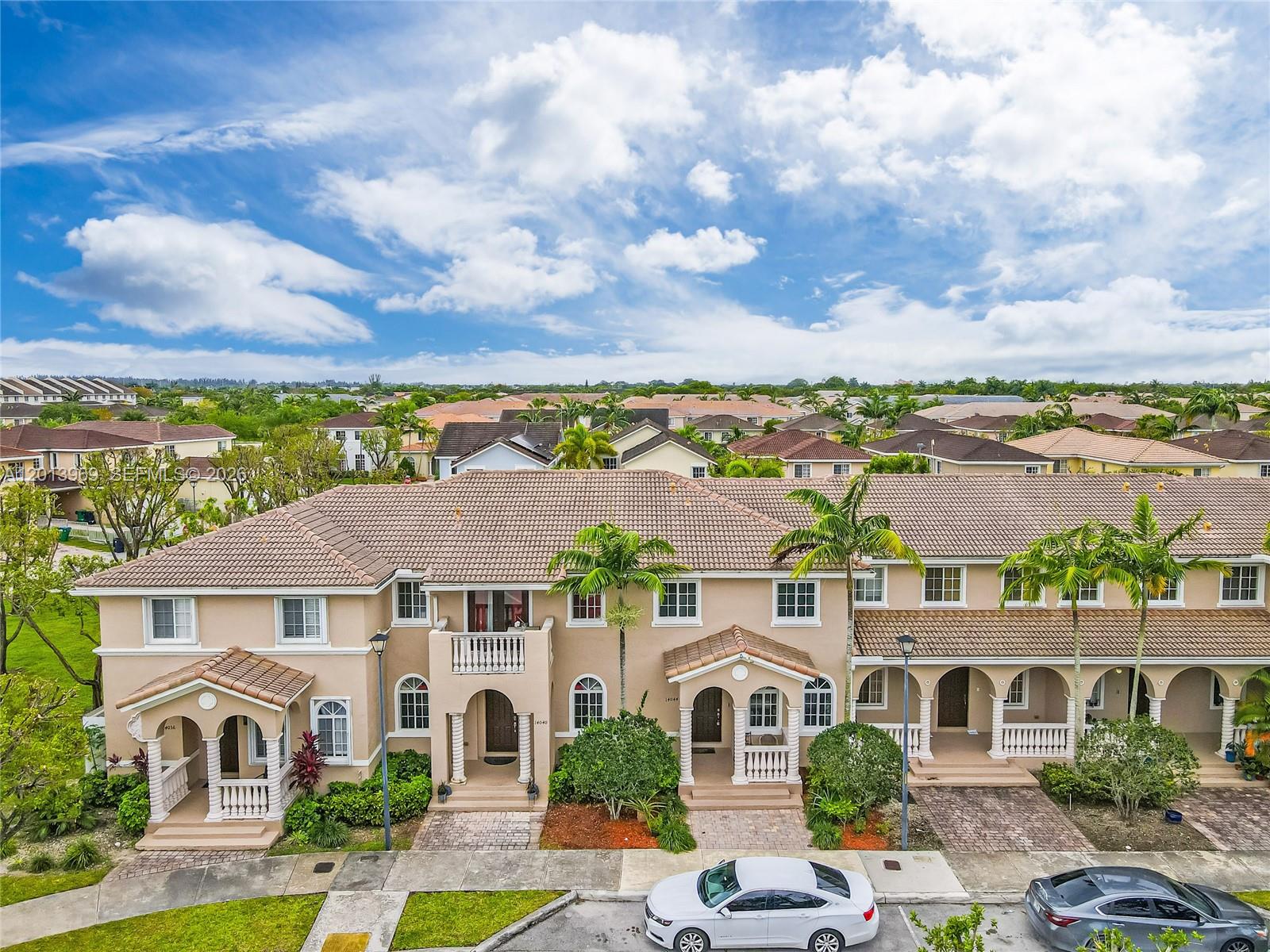 14044 Southwest 273rd Lane, Unit 14044 Homestead, FL 33032 - Photo 2 of 44 a view of a white house with a big yard plants and large trees