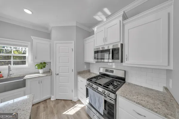 a kitchen with stainless steel appliances white cabinets and a stove top oven