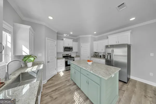 a kitchen with stainless steel appliances kitchen island granite countertop a refrigerator and a sink