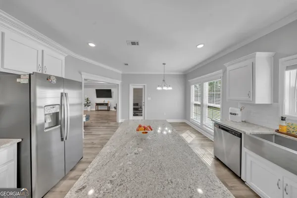 a large kitchen with stainless steel appliances kitchen island granite countertop a refrigerator and a sink