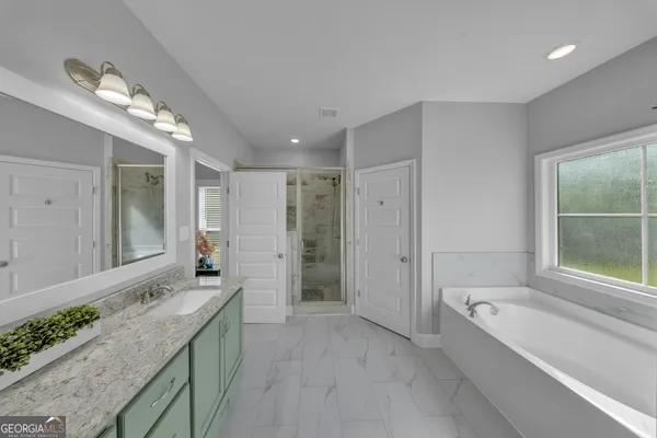 a large spacious bathroom with a granite countertop tub shower and mirror