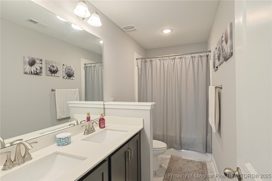 7810 Rufus Johnson Road St. Pauls, NC 28384 - Photo 14 of 24 a bathroom with a sink vanity mirror and toilet