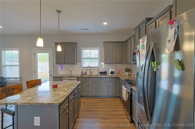 a kitchen with stainless steel appliances granite countertop a sink a stove and a refrigerator