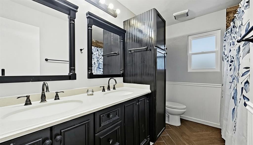 5016 St Lawrence Road Fort Worth, TX 76103 - Photo 18 of 22 a bathroom with a double vanity sink toilet and mirror