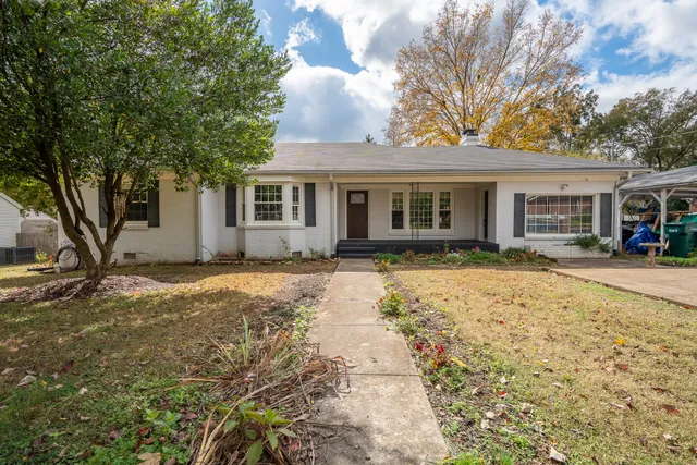 a front view of a house with a yard and trees