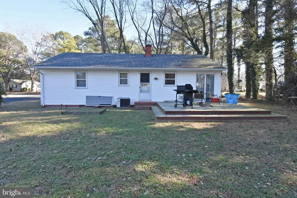 a front view of house with yard and trees in the background