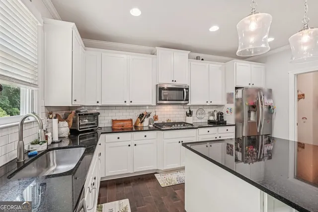 a kitchen with stainless steel appliances granite countertop a sink a stove and a refrigerator
