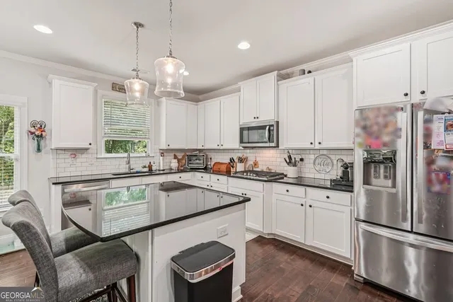 a kitchen with stainless steel appliances granite countertop a sink a stove a refrigerator cabinets and chairs