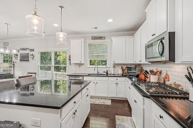 a kitchen with kitchen island granite countertop a sink a counter space appliances and cabinets