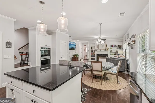 a kitchen with stainless steel appliances granite countertop a stove a sink a dining table and chairs with wooden floor