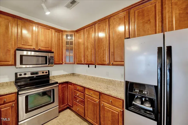 a kitchen with stainless steel appliances granite countertop a refrigerator and a stove top oven