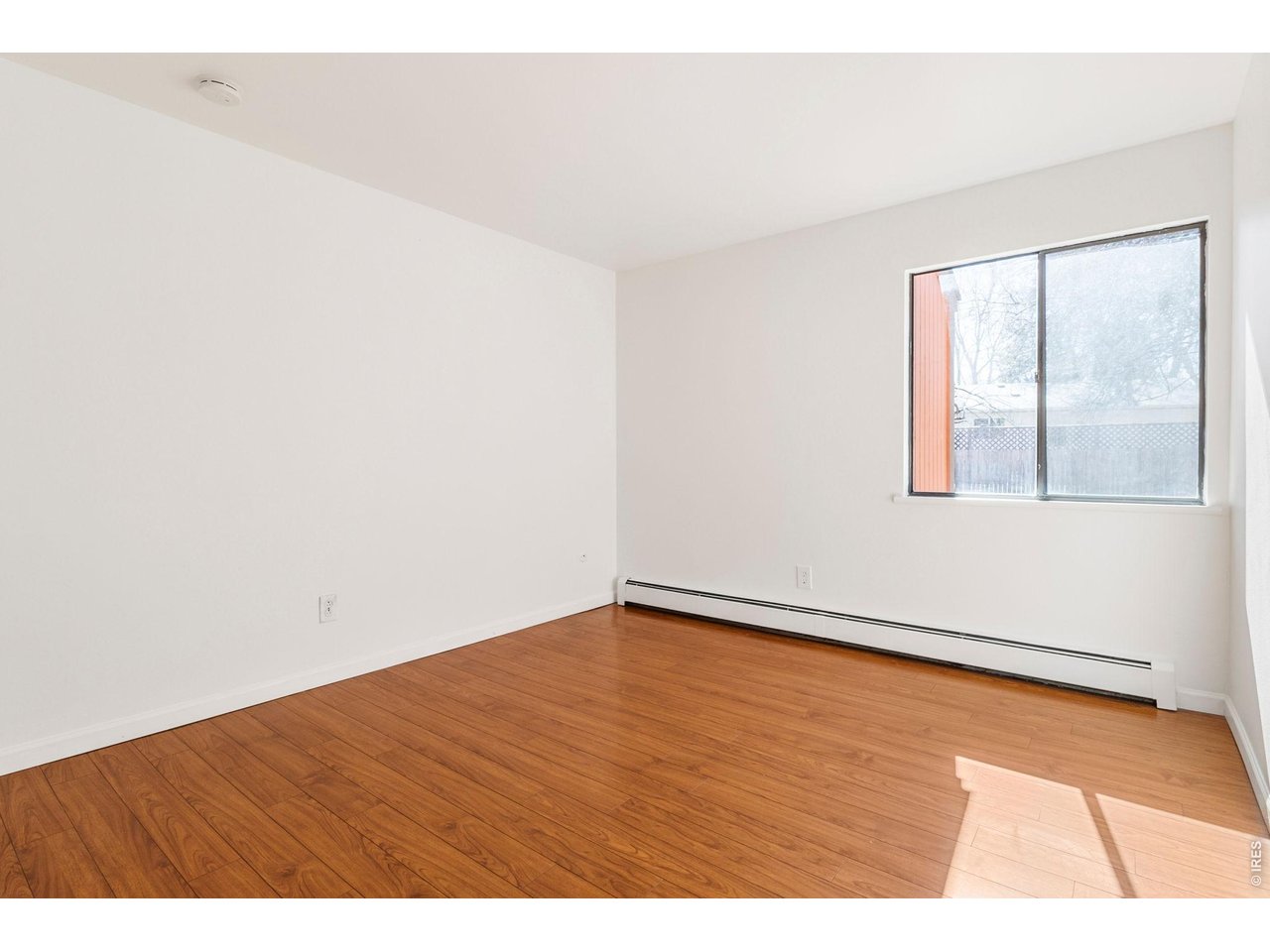 1625 West Elizabeth Street, Unit 1 Fort Collins, CO 80521 - Photo 11 of 16 a view of an empty room with wooden floor and a window