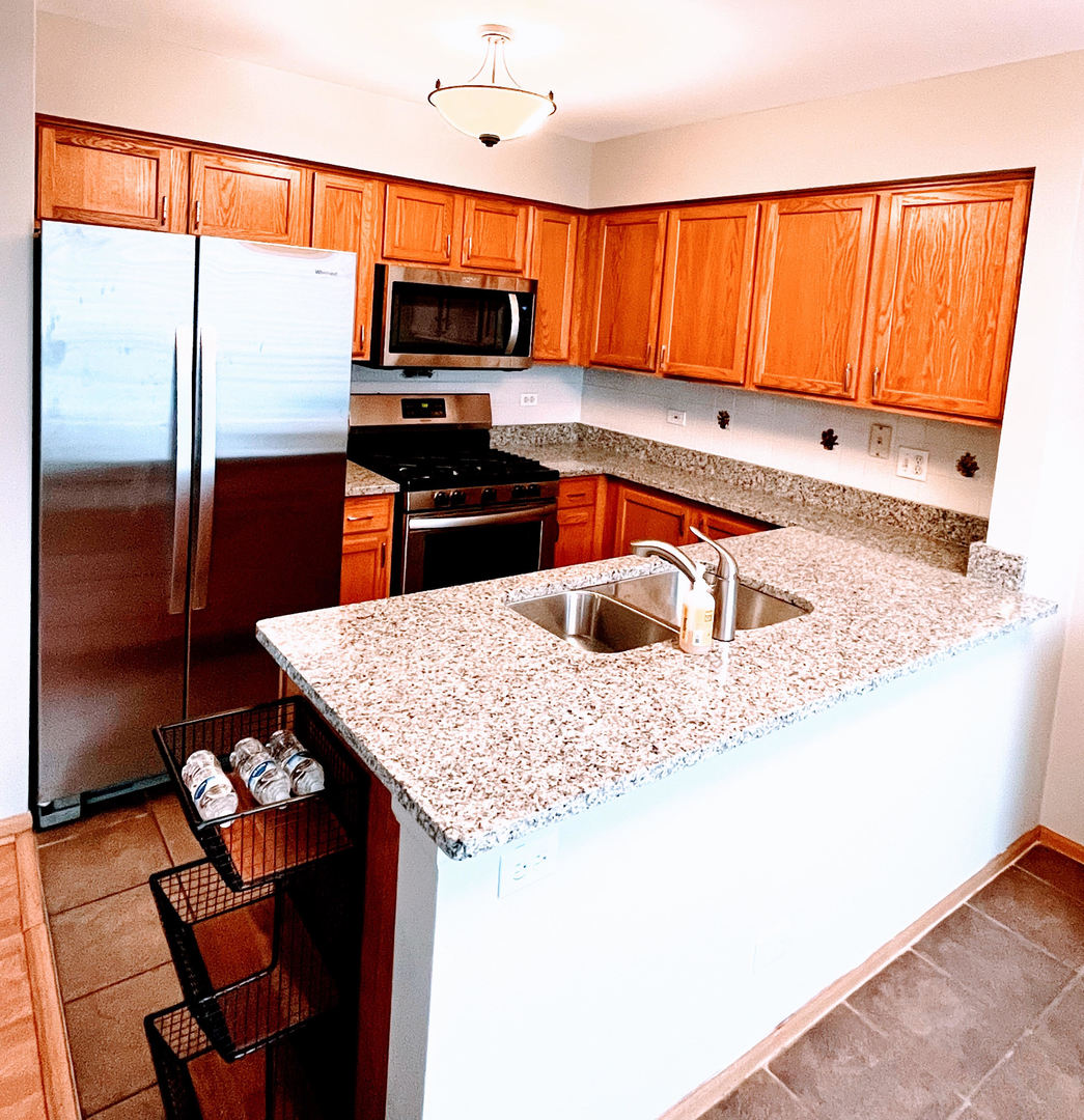 3159 Cambria Court Aurora, IL 60503 - Photo 3 of 21 a kitchen with stainless steel appliances granite countertop a sink refrigerator and microwave