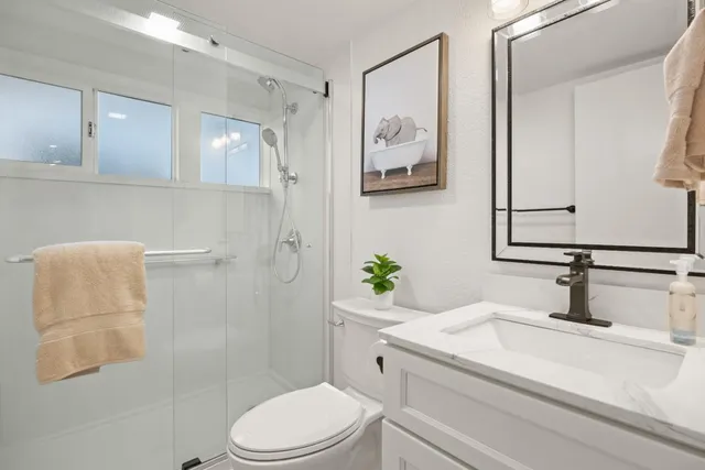a bathroom with a granite countertop sink toilet and shower