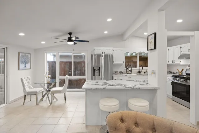 a large white kitchen with a large window and stainless steel appliances