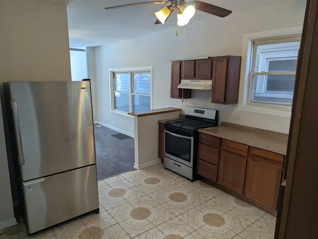 a kitchen with stainless steel appliances granite countertop a refrigerator a stove and a sink