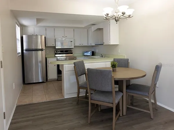 a kitchen with stainless steel appliances granite countertop a dining table chairs refrigerator and cabinets