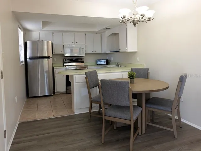 a kitchen with stainless steel appliances granite countertop a dining table chairs refrigerator and cabinets