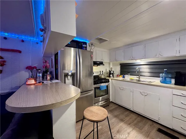 a kitchen with stainless steel appliances a sink a table and chairs