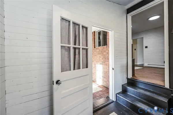a view of a hallway with wooden floor and a bathroom