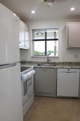 a kitchen with granite countertop white cabinets and a sink
