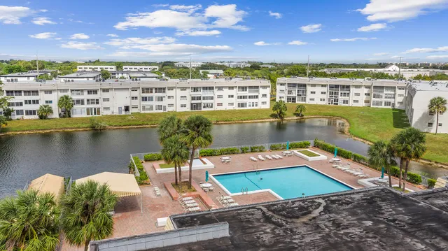 a view of a large pool with a lawn chairs and wooden floor