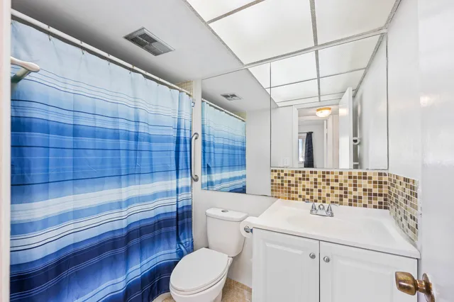 a bathroom with a granite countertop shower sink vanity and toilet