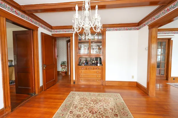 a hallway with wooden floor and chandelier