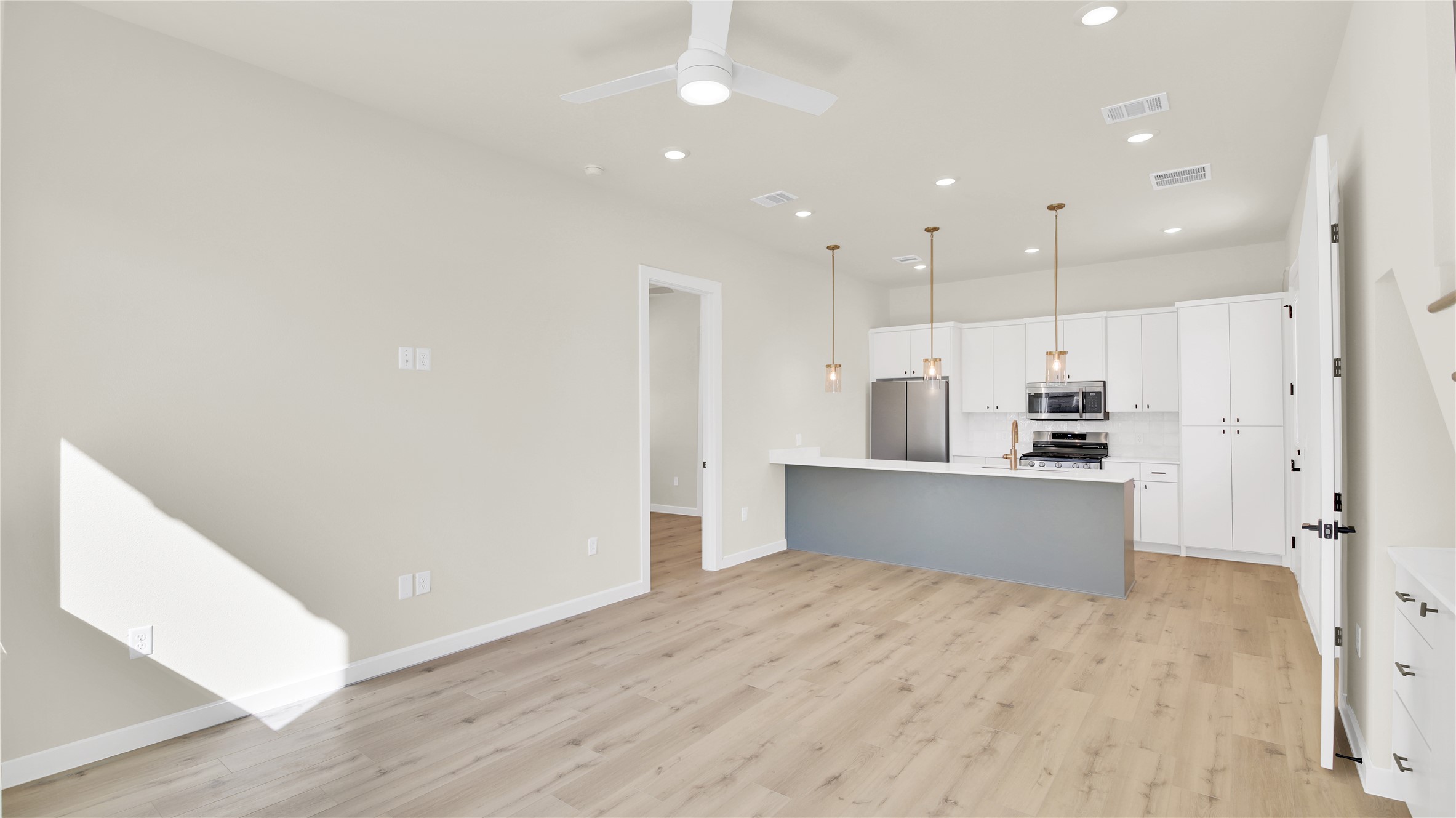 6802 Montana Street, Unit 1 Austin, TX 78741 - Photo 19 of 20 Kitchen with white cabinetry, decorative light fixtures, stainless steel appliances, open floor plan, and light wood-style flooring