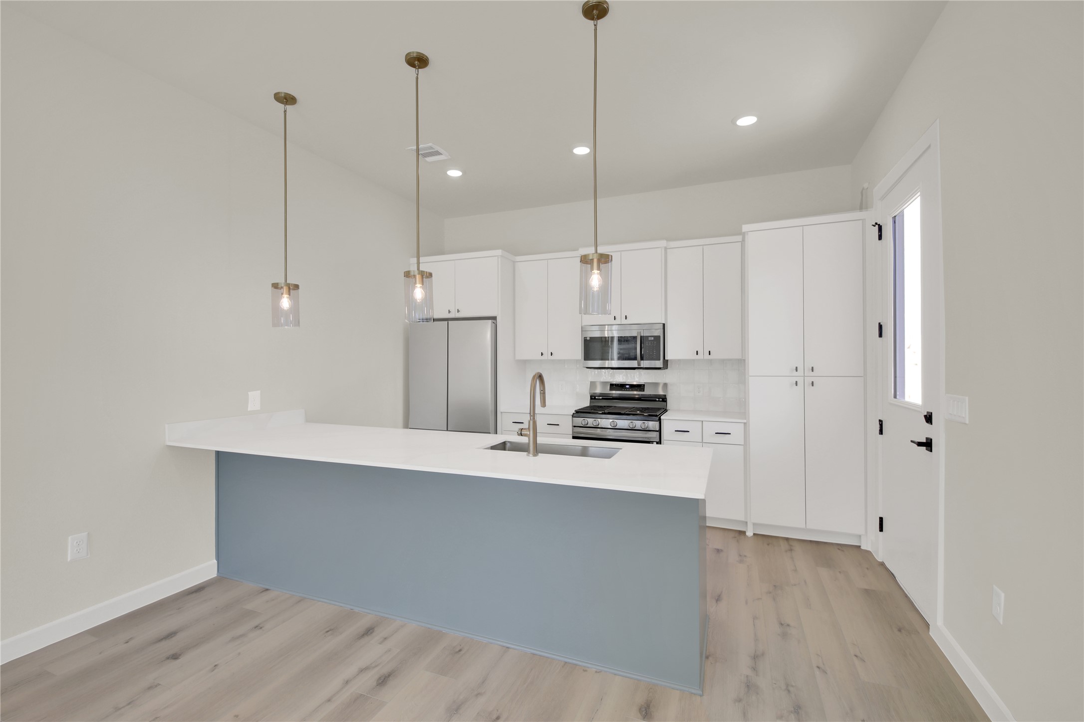 6802 Montana Street, Unit 1 Austin, TX 78741 - Photo 5 of 20 Kitchen with a peninsula, white cabinets, stainless steel appliances, pendant lighting, and tasteful backsplash