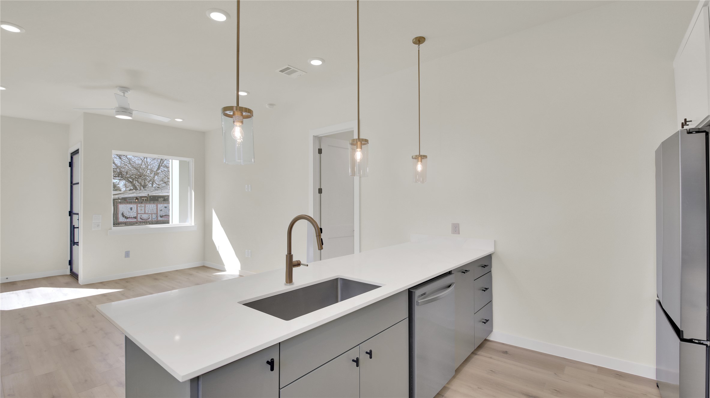 6802 Montana Street, Unit 1 Austin, TX 78741 - Photo 7 of 20 Kitchen with a peninsula, freestanding refrigerator, gray cabinetry, decorative light fixtures, and light wood-type flooring