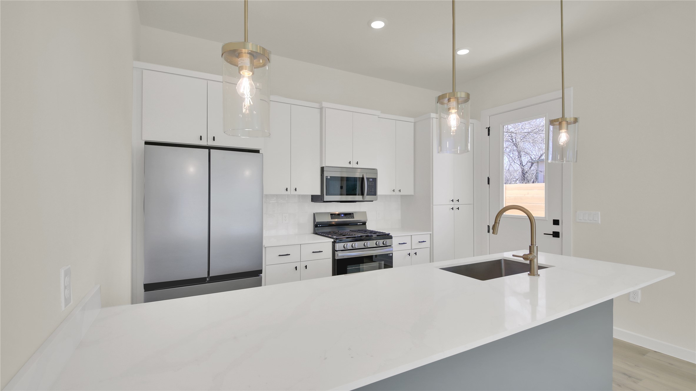 6802 Montana Street, Unit 1 Austin, TX 78741 - Photo 8 of 20 Kitchen featuring stainless steel appliances, decorative light fixtures, white cabinets, and light stone counters