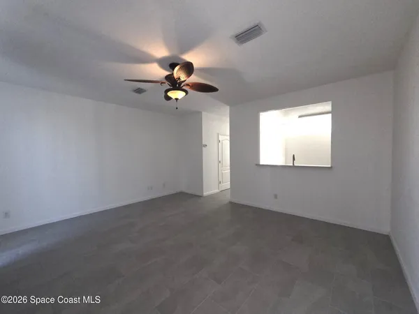 an empty room with a window and a fan