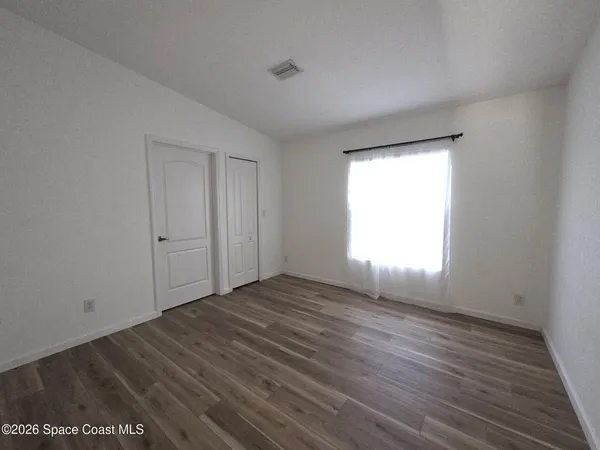 an empty room with wooden floor and windows
