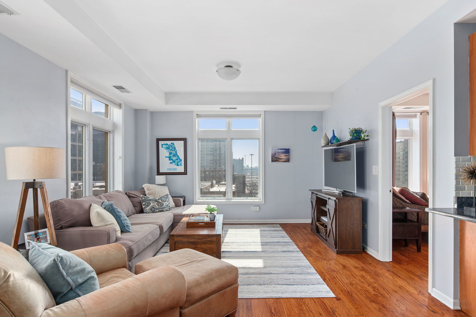 657 West Fulton Street, Unit 705 Chicago, IL 60661 - Photo 4 of 24 a living room with furniture a large window wooden floor and a flat screen tv