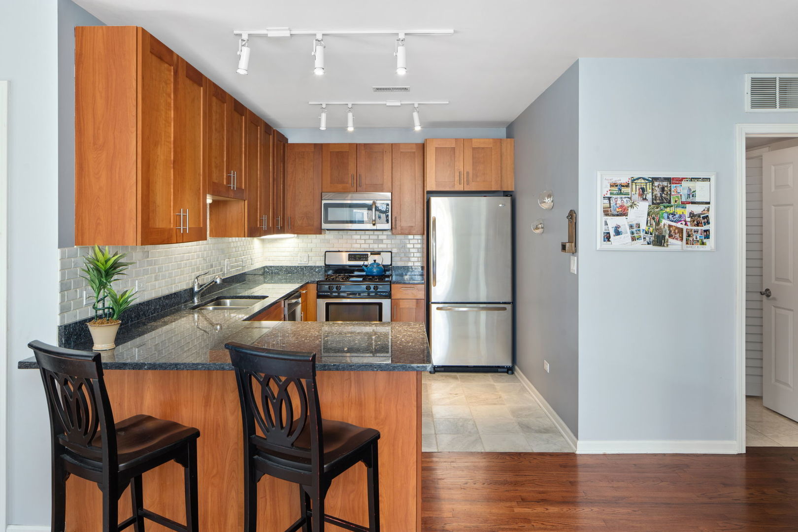 657 West Fulton Street, Unit 705 Chicago, IL 60661 - Photo 10 of 24 a kitchen with stainless steel appliances granite countertop a refrigerator a stove a sink a dining table and chairs with wooden floor