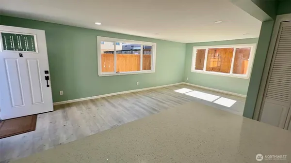 a view of an empty room with window and wooden floor