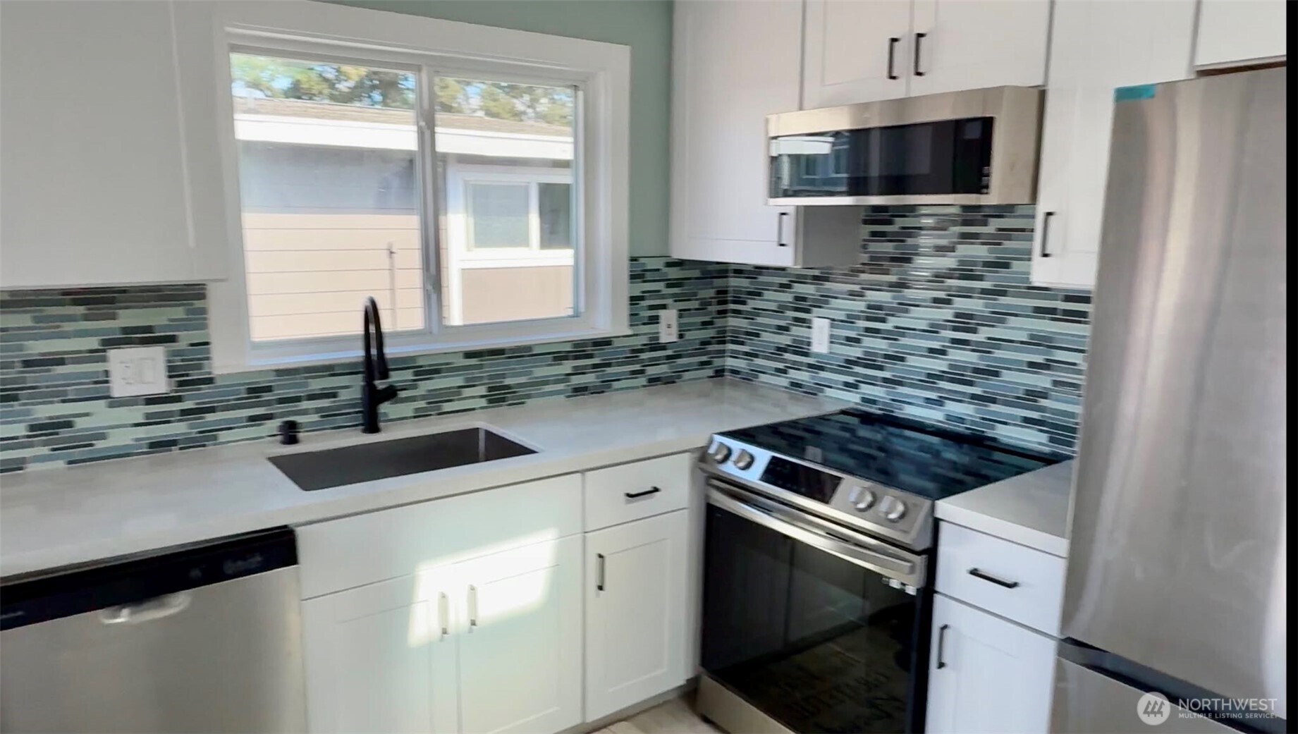 9040 17th Avenue Southwest Seattle, WA 98106 - Photo 10 of 34 a kitchen with stainless steel appliances a sink stove and microwave