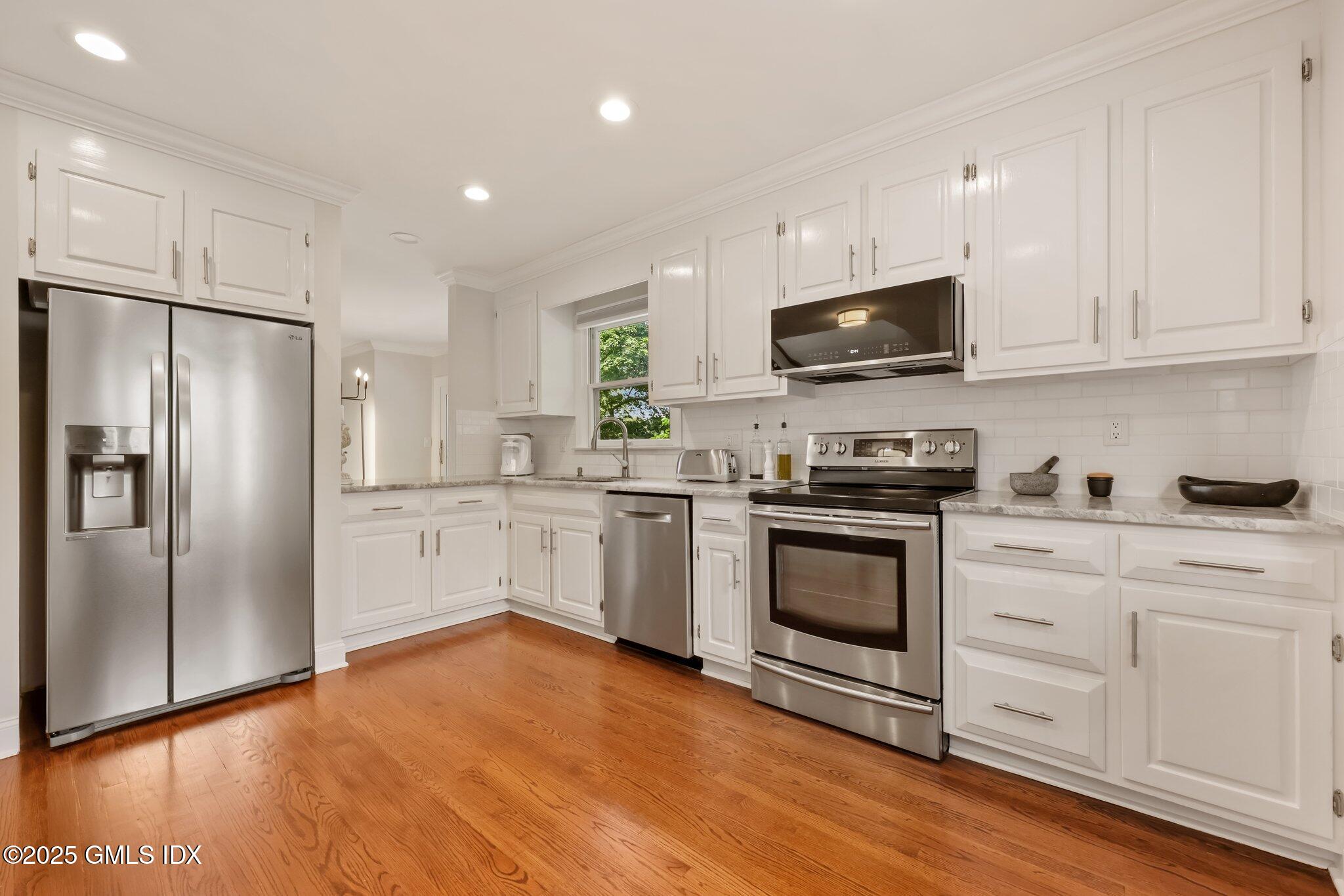 172 Field Point Road, Unit 9 Greenwich, CT 06830 - Photo 9 of 20 a kitchen with white cabinets stainless steel appliances and wooden floor