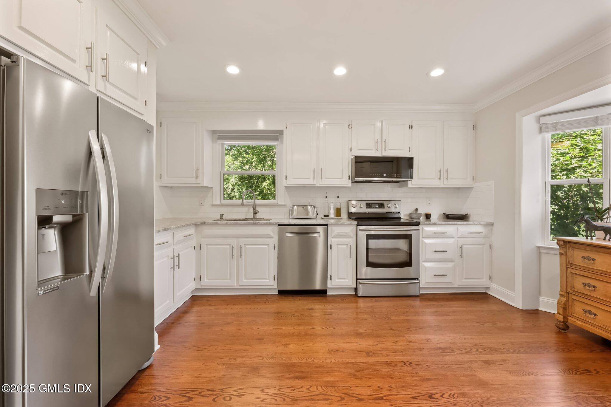 172 Field Point Road, Unit 9 Greenwich, CT 06830 - Photo 10 of 20 a kitchen with white cabinets and stainless steel appliances