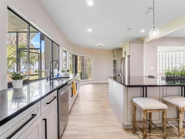a kitchen with stainless steel appliances kitchen island granite countertop a dining table chairs and sink