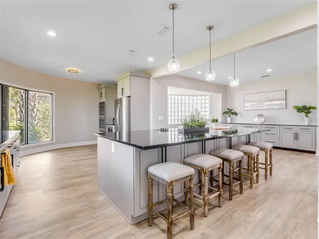 a kitchen with granite countertop a refrigerator a sink and white cabinets