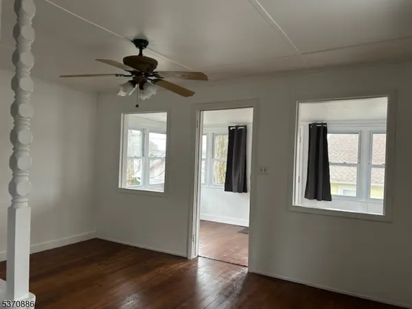a view of an empty room with a window and wooden floor