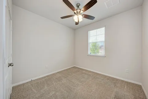 an empty room with a window and a fan