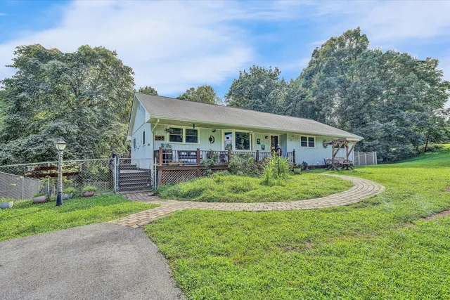 a view of house in front of a big yard with large trees
