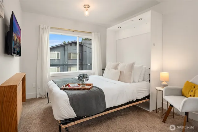 a bedroom with a bed a flat screen tv and windows