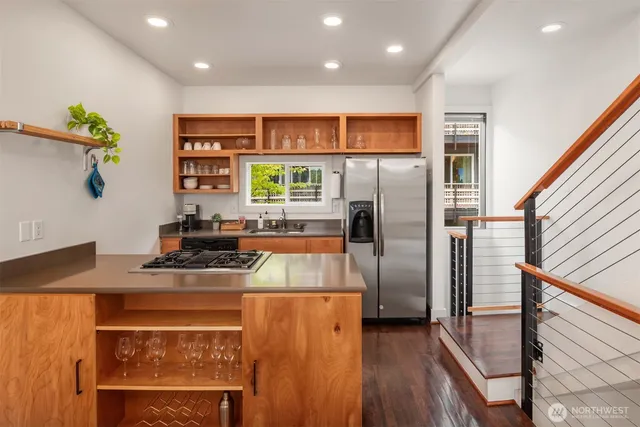 a kitchen with stainless steel appliances granite countertop a refrigerator a stove and a sink with wooden floor